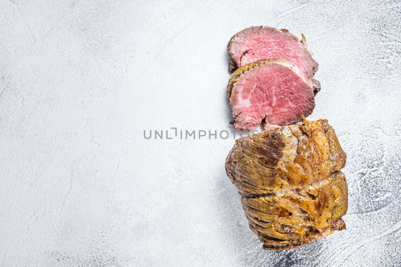 Roast beef meat fillet on kitchen table. White background. Top view. Copy space by Composter