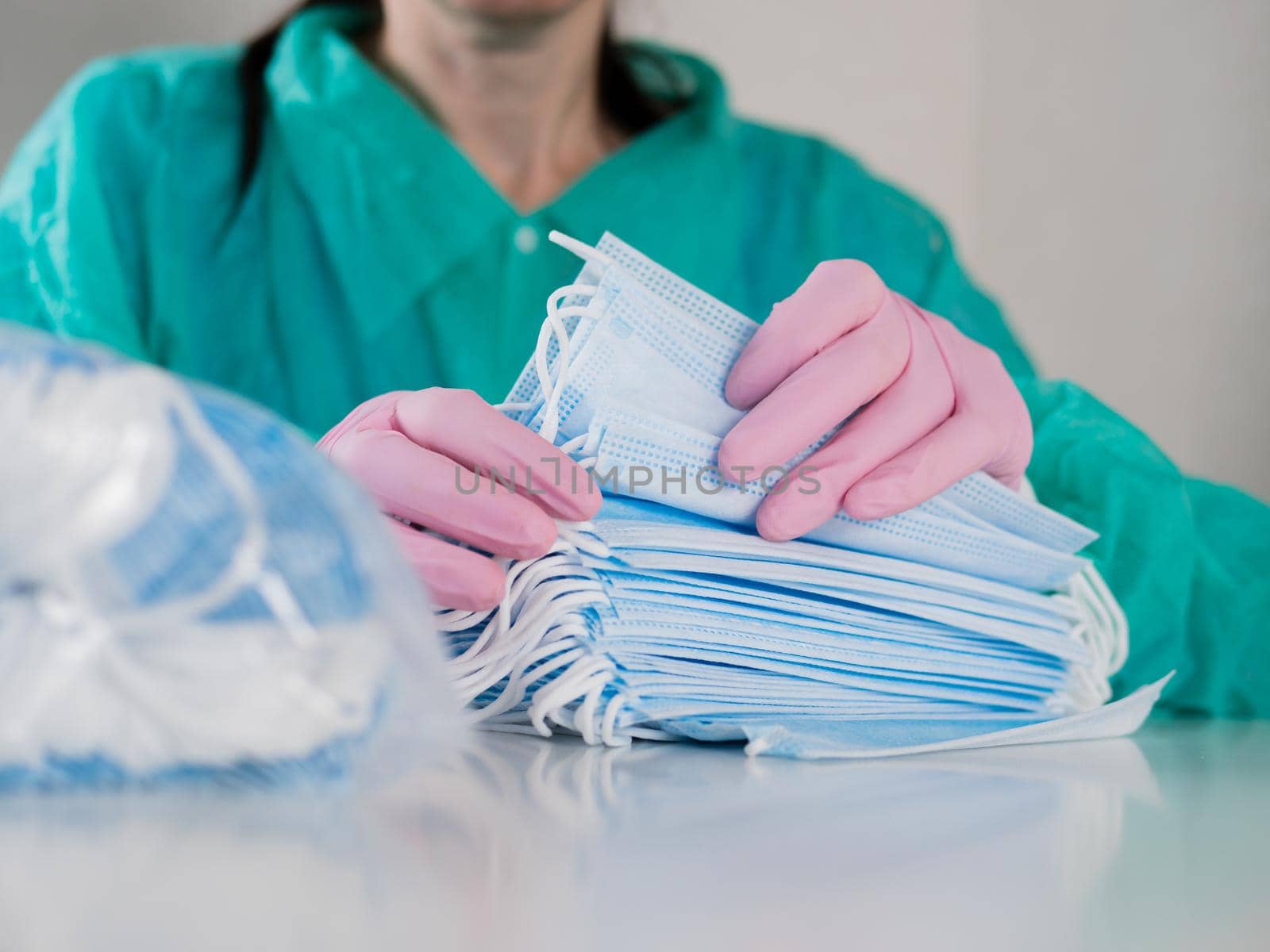 A woman in pink gloves counts medical disposable masks, close-up