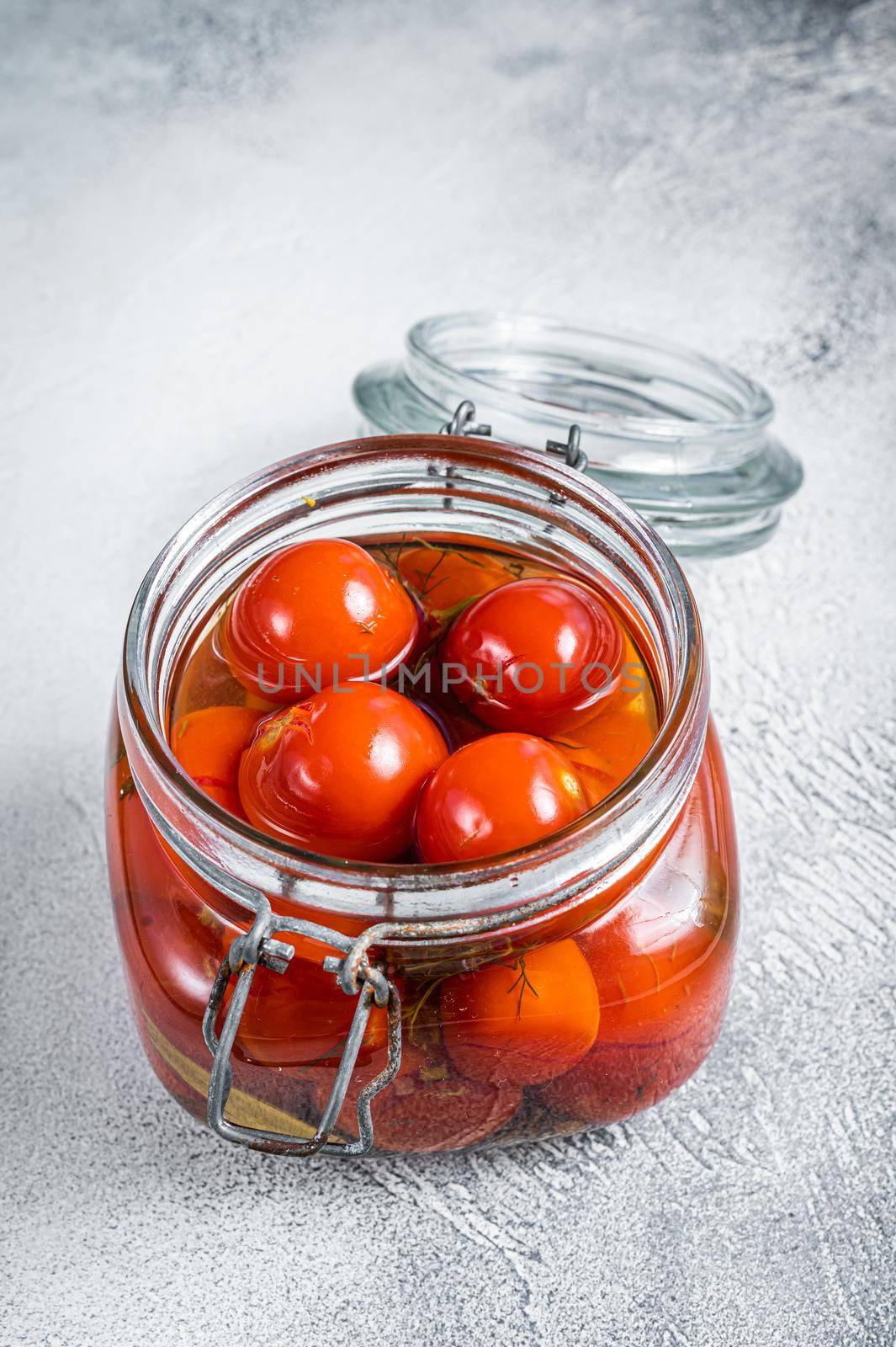 Pickled cherry tomatoes in a glass jar. White background. Top view.