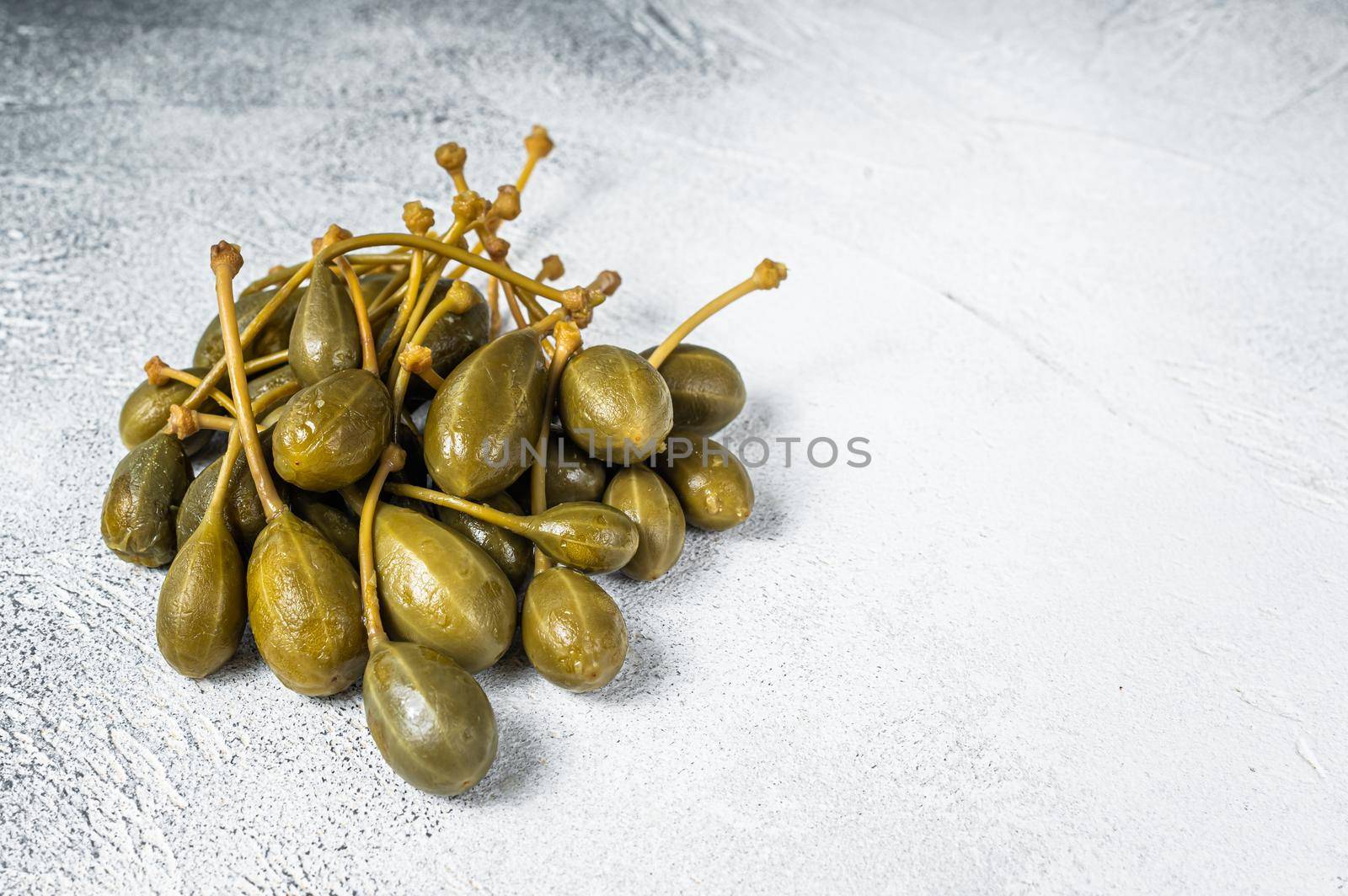 Pickled capers on a kitchen table. White background. Top view. Copy space.