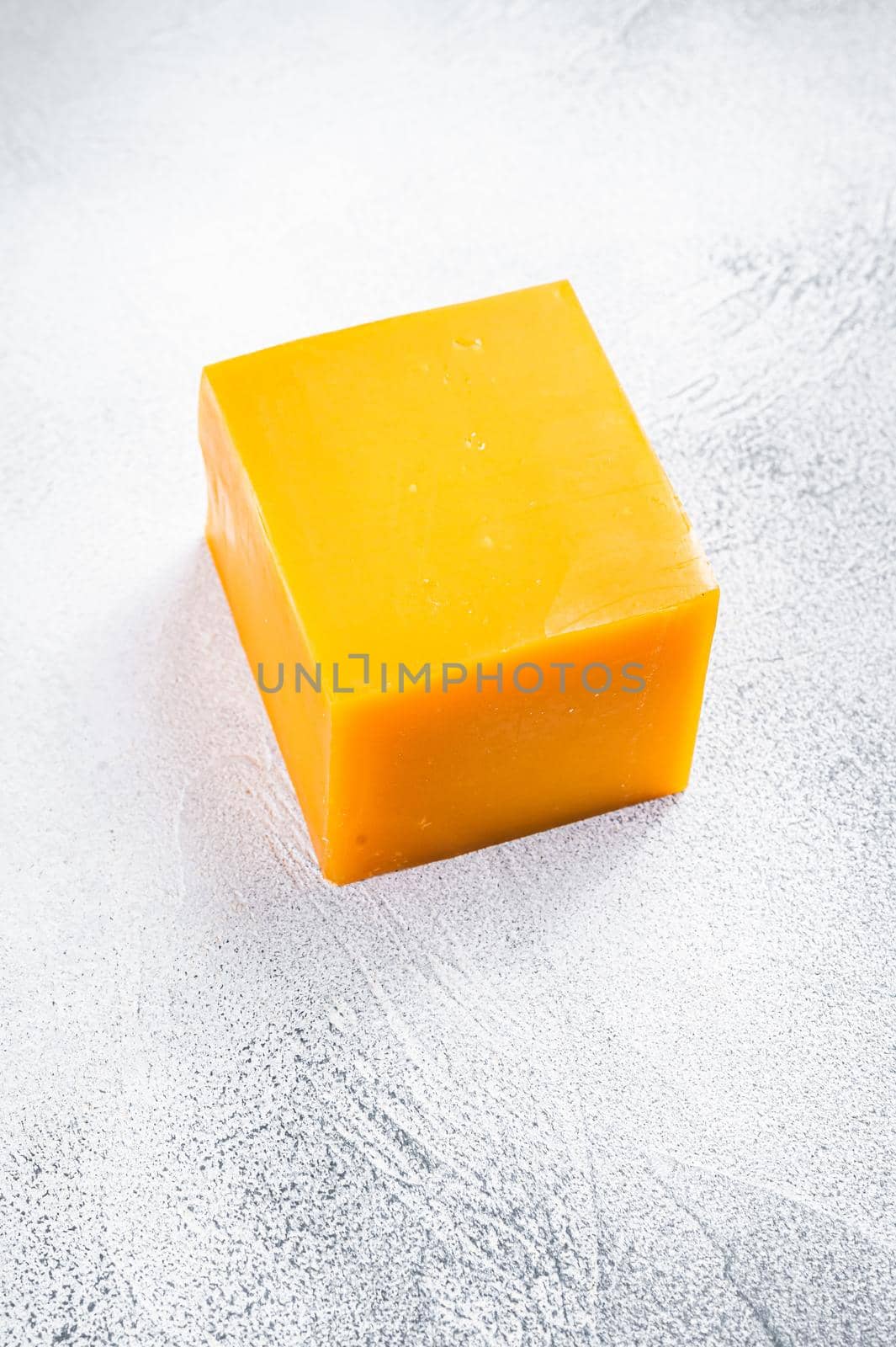 Cheddar Cheese block on a kitchen table. White background. Top view.
