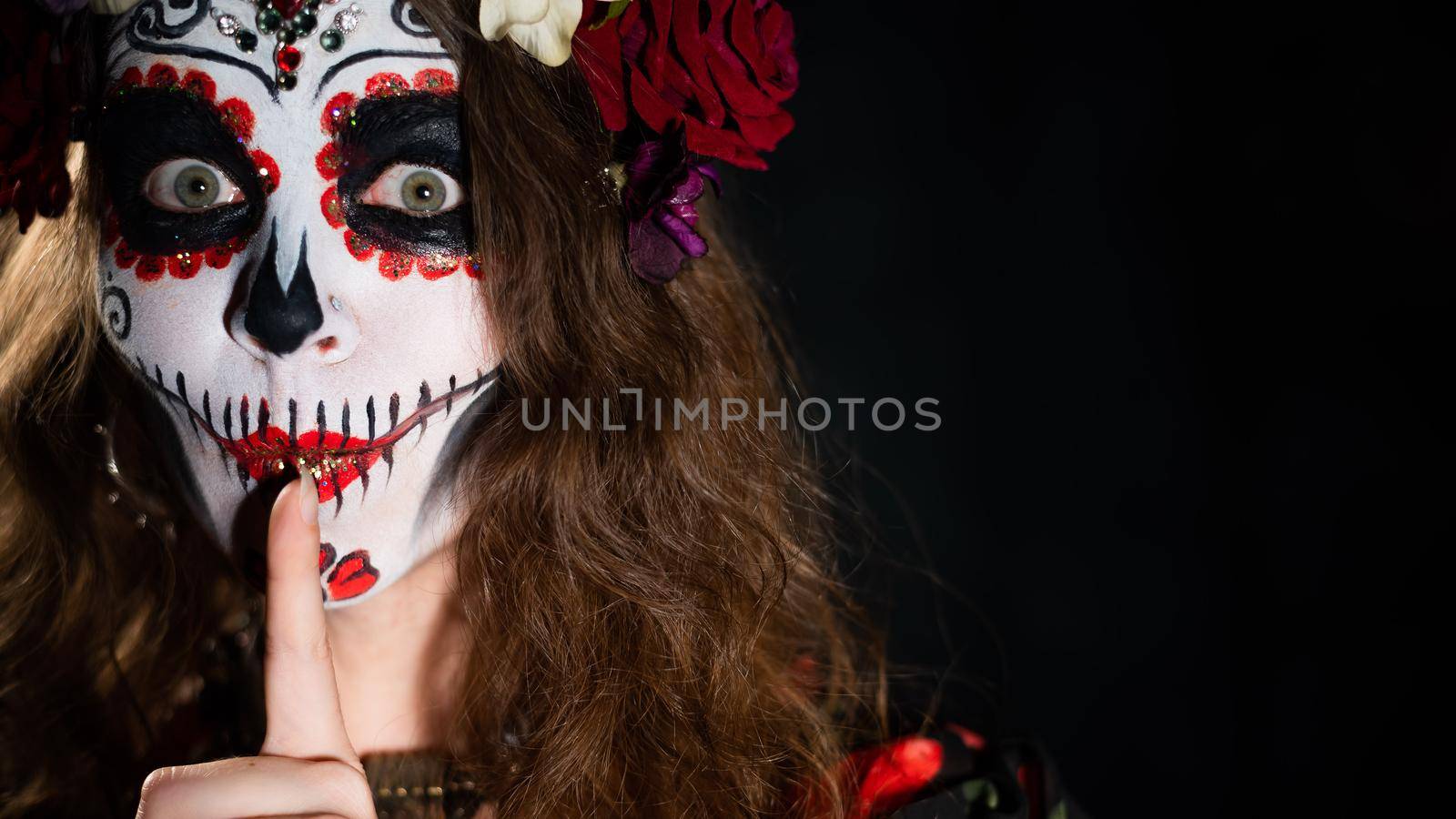 Woman in santa muerte makeup on a black background. Girl wearing traditional mexican holy death costume for halloween. Copy space.