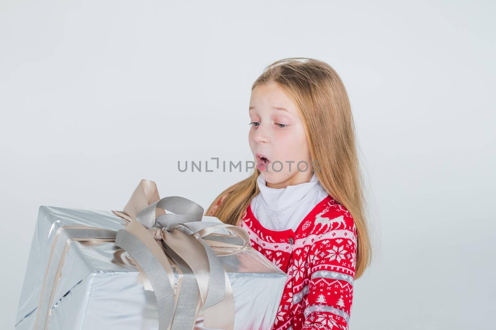 Joyous girl holding gift-wrapped box being excited and surprised to get present on white background.holidays, present, christmas, childhood, happiness concept.Excited surprised young girl in red dress by YuliaYaspe1979