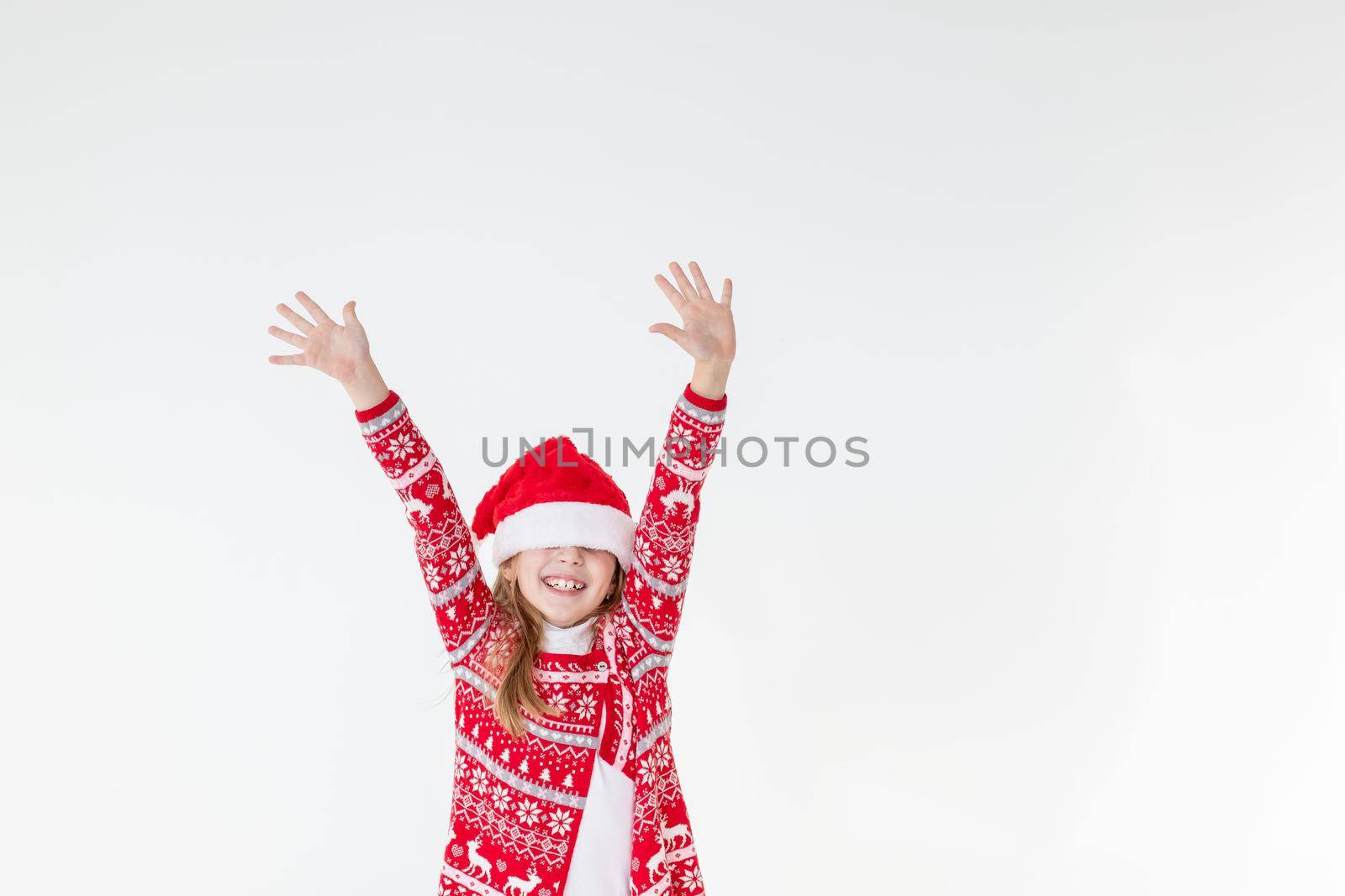 Cute funny santa's helper dancing on white background. Christmas holidays concept.New Year celebration. funny baby Santa.beautiful girl wearing red santa hat celebrating christmas day ,having fun. by YuliaYaspe1979