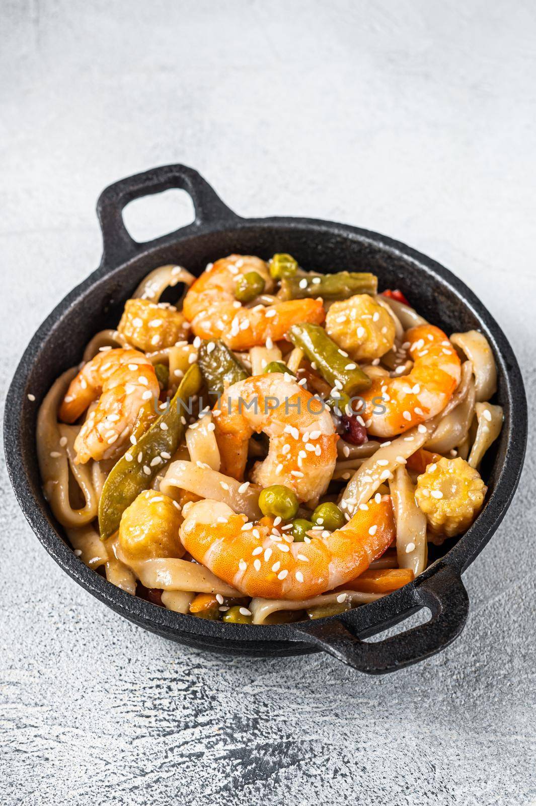 Udon stir-fry noodles with shrimps prawns in a pan. White background. Top view.