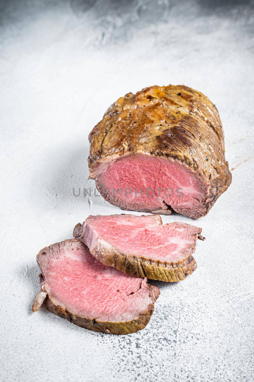 Roast beef meat fillet on kitchen table. White background. Top view by Composter