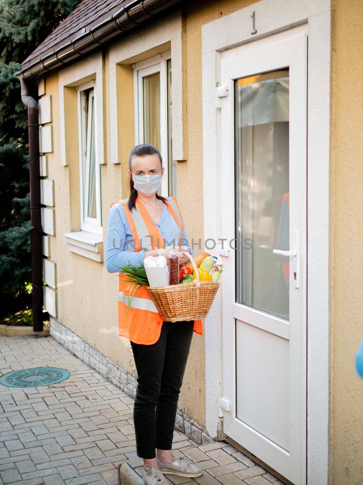 Food delivery at home during the pandemic. Delivery of a basket of vegetables. A volunteer delivers food in a basket. by Utlanov