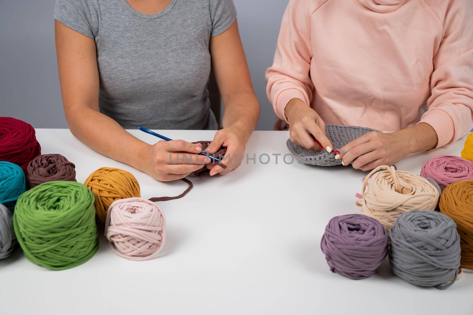 A woman teaches her friend needlework. Two women are crocheting a basket of cotton yarn. by mrwed54