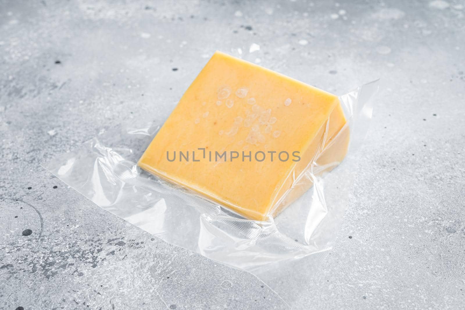 Organic Sharp Cheddar Cheese in vacuum packaging. Gray background. Top view by Composter