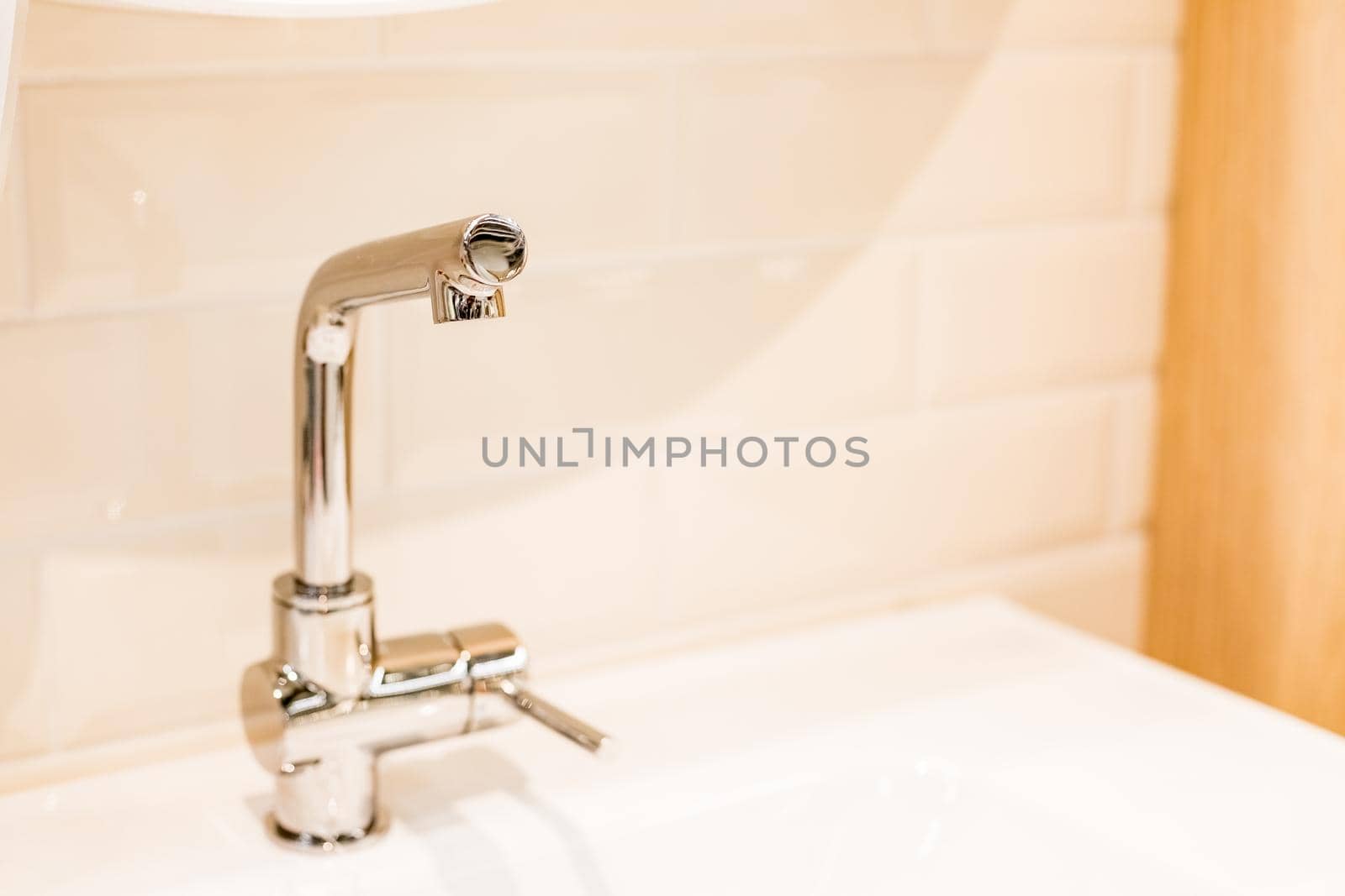 Luxury faucet mixer and white towel on a white sink in a beautiful gray bathroom. Sanitary prevention antivirus concept.