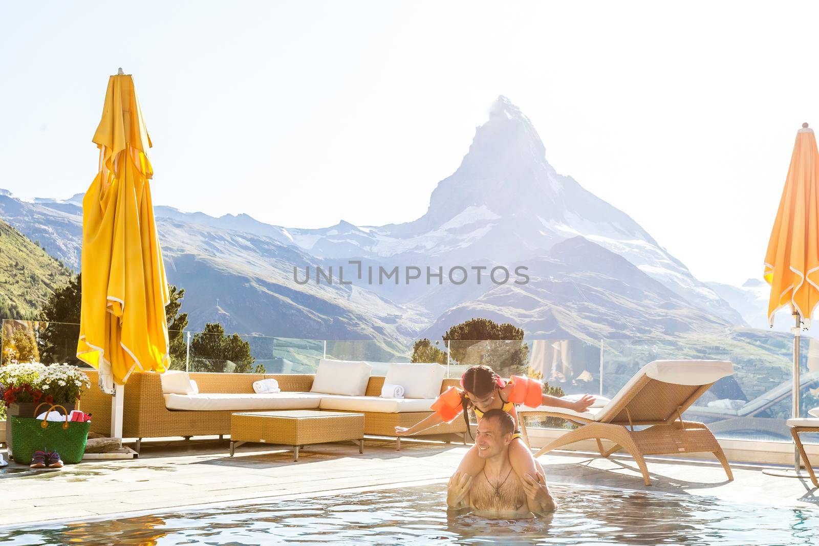 Family In Swimming Pool In Mountains. Beautiful outdoor scene in Swiss Alps, Switzerland, Europe. by Andelov13