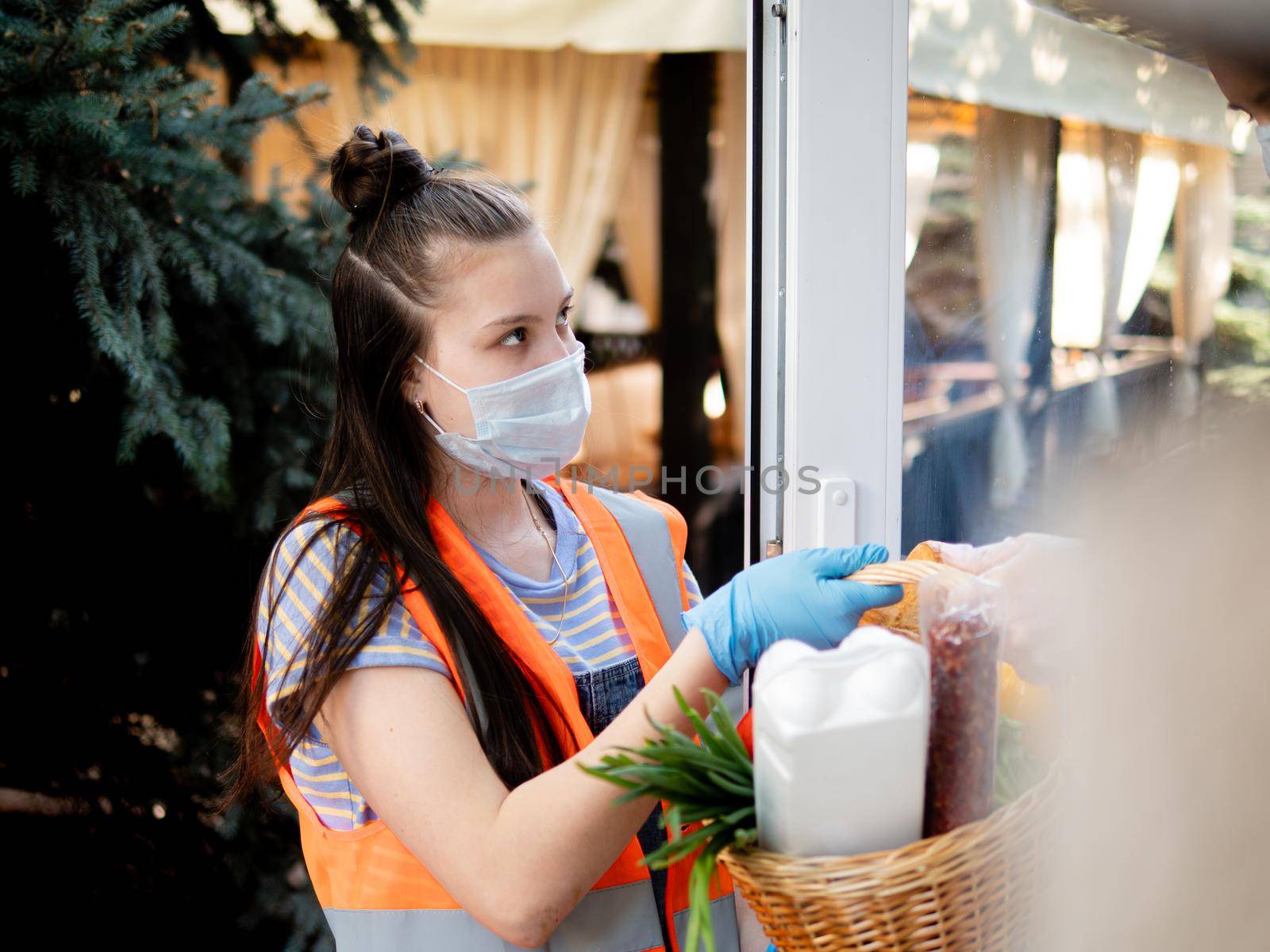 Teen girl volunteer delivers food to the house during the quarantine.