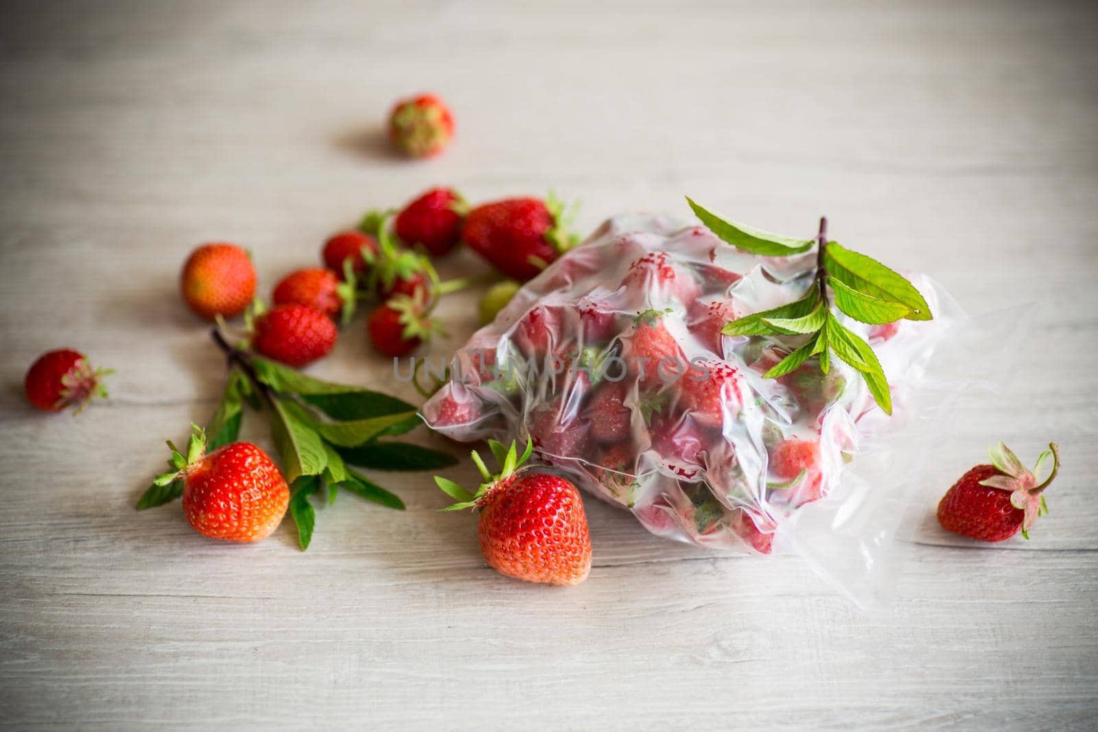frozen fresh strawberries in a vacuum bag on a wooden table