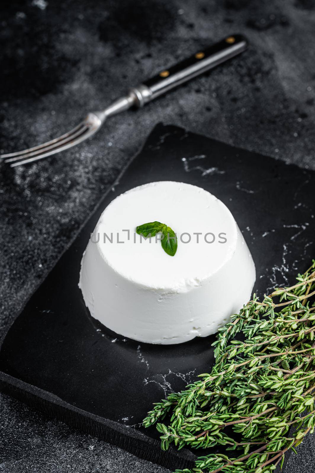 Ricotta cream Cheese on marble board with thyme. Black background. Top view.