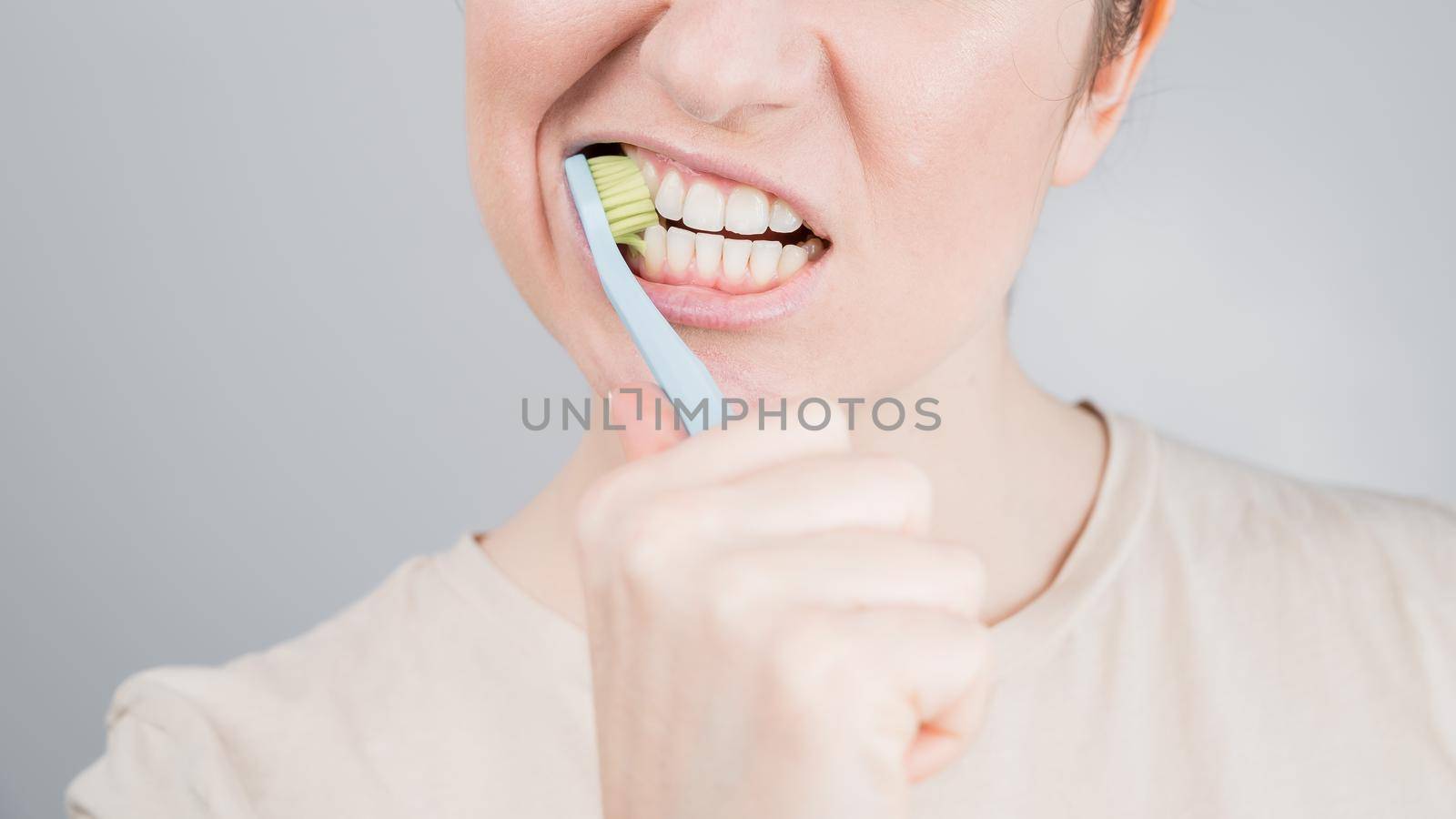 Close-up portrait of caucasian woman brushing her teeth. The girl performs the morning oral hygiene procedure.