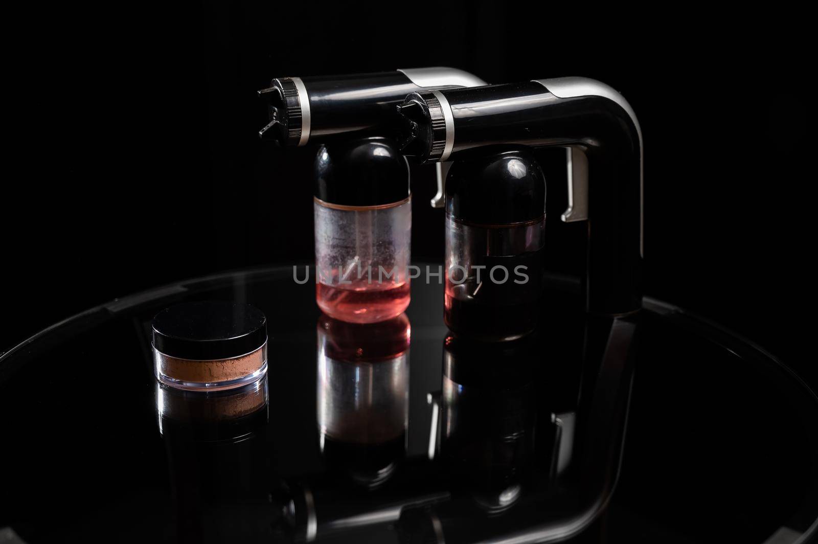 A close-up of the instant tanning equipment. Gun spraying paint for leather, brush and matting body powder on a black background. by mrwed54
