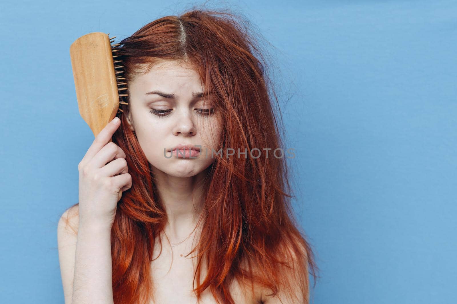 pretty woman combing naughty hair blue background. High quality photo