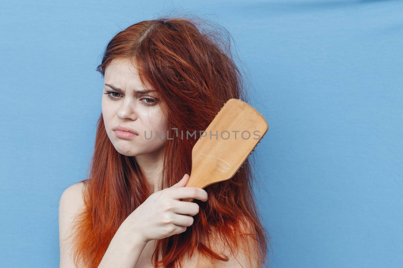 pretty woman combing naughty hair blue background. High quality photo