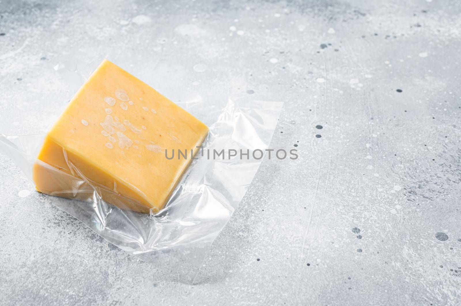 Organic Sharp Cheddar Cheese in vacuum packaging. Gray background. Top view. Copy space.