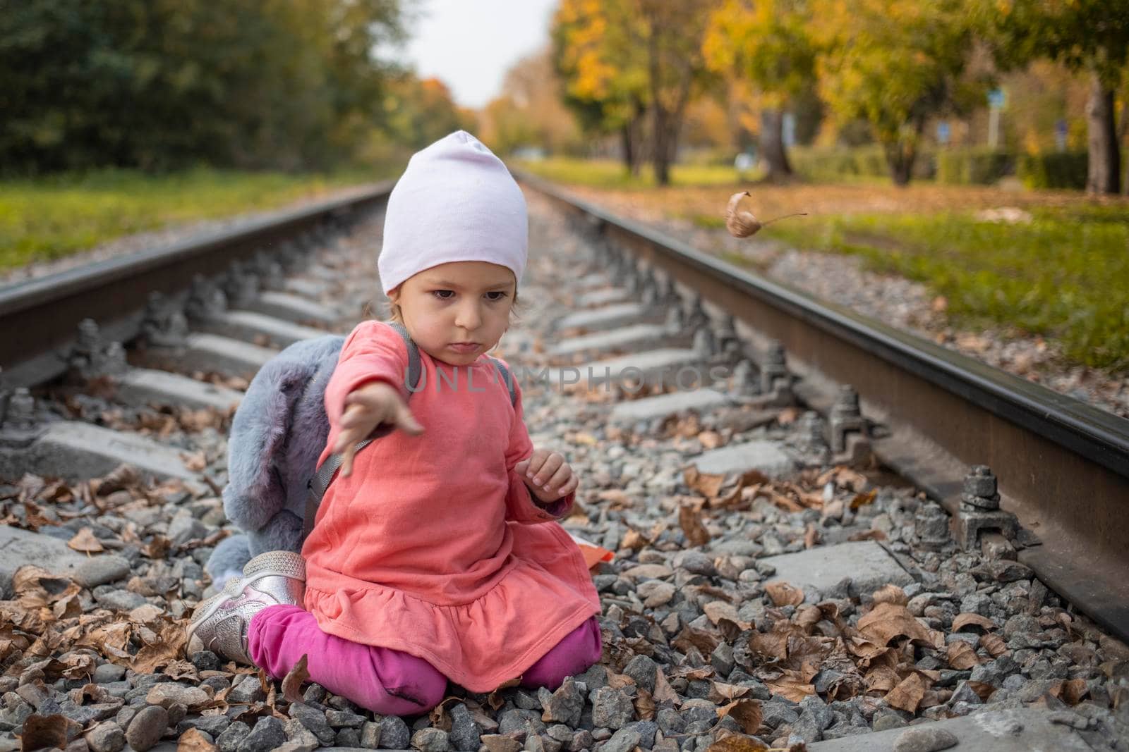 portrait of little girl sitting on the train tracks in the forest