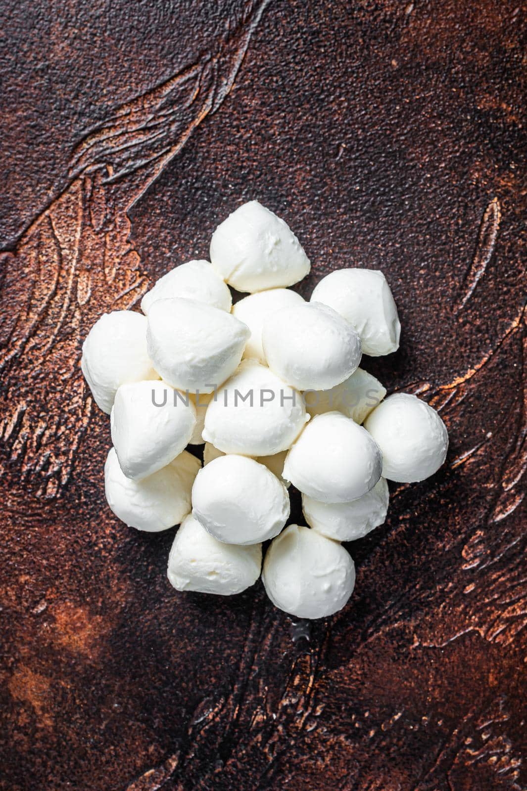 Buffalo mozzarella cheese mini balls on kitchen table. Dark background. Top view.