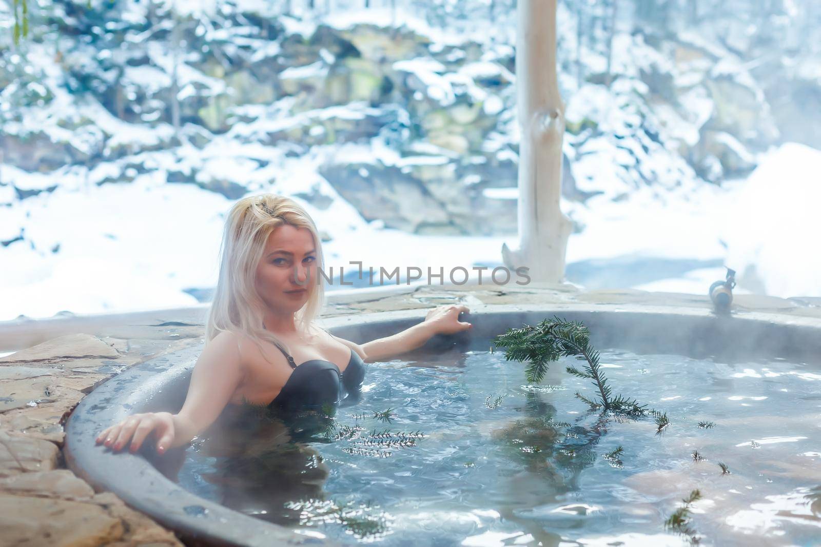 Young lady relaxing outside in thermal bath in winter