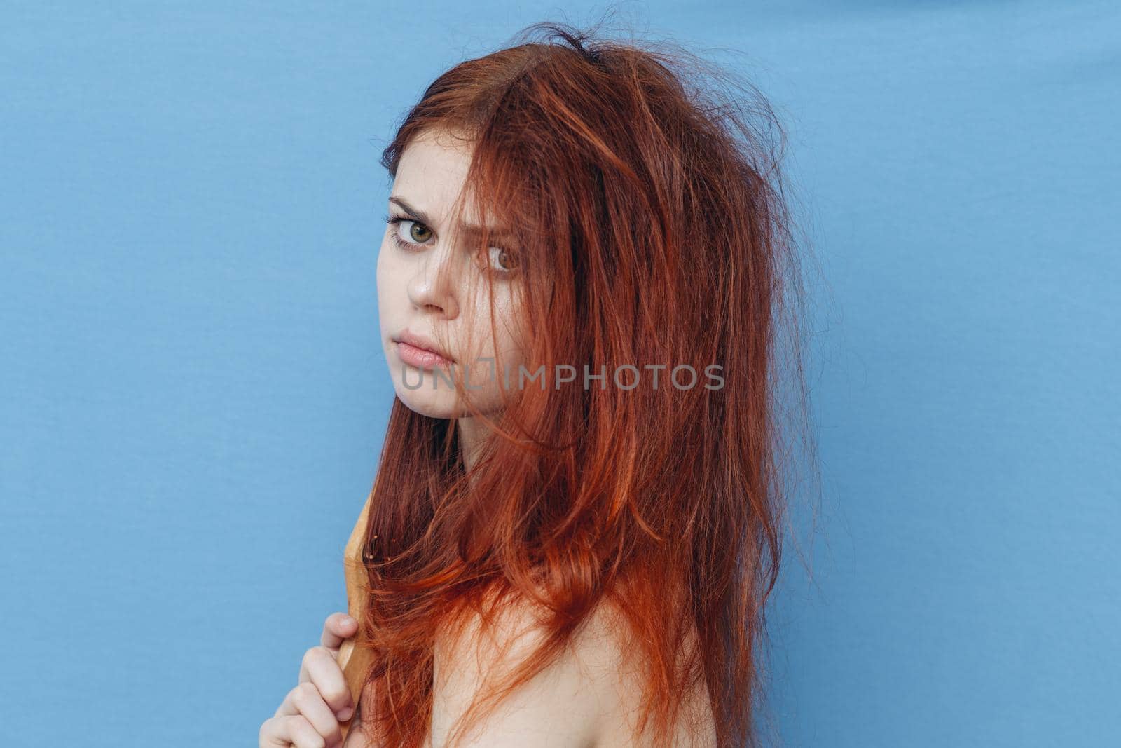pretty woman combing naughty hair blue background by Vichizh