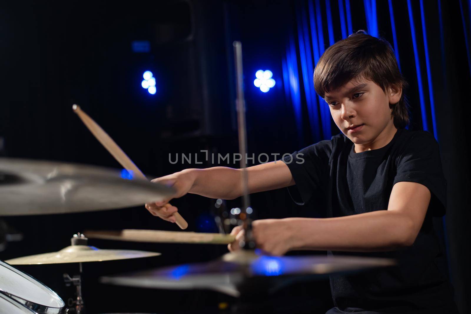 A boy plays drums in a recording studio.