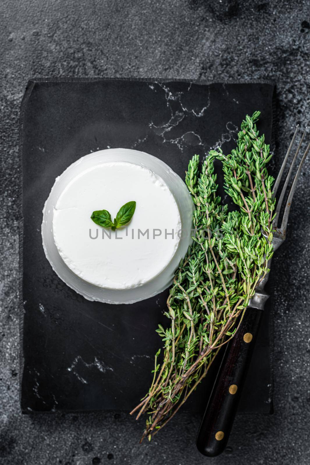 Ricotta cream Cheese on marble board with thyme. Black background. Top view by Composter