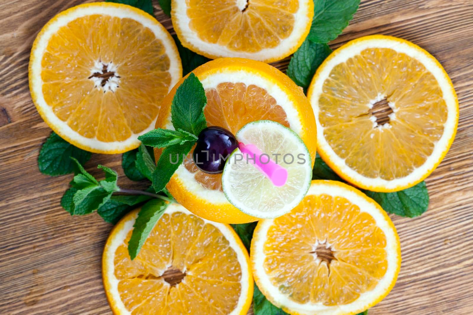 close-up photo of an orange cut into slices. Pieces of fruit lie on an old wooden table