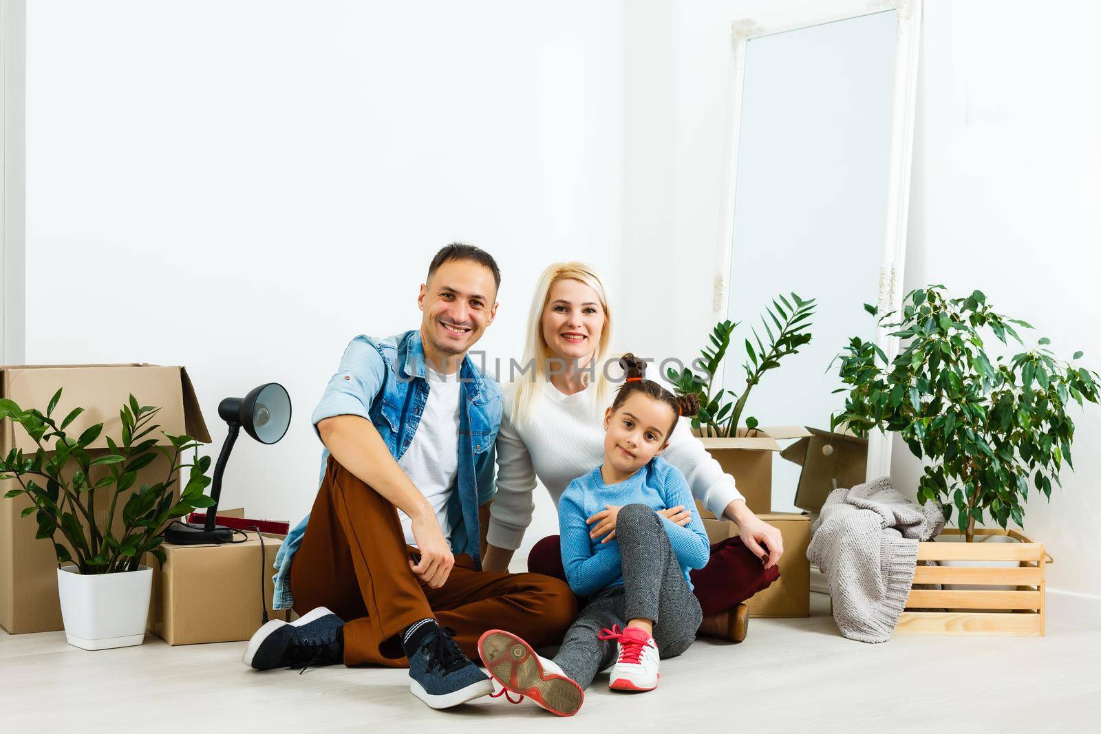 Family unpacking cardboard boxes at new home by Andelov13