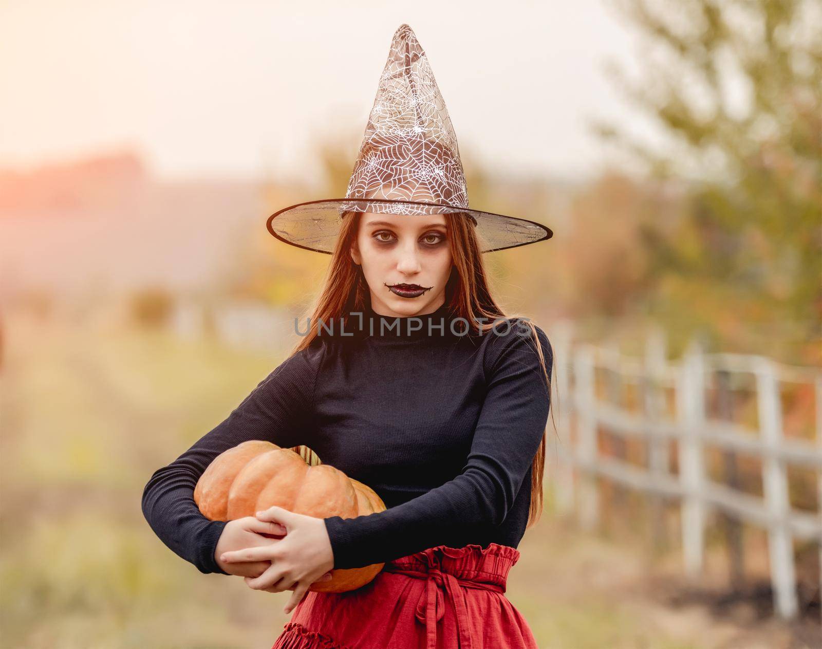 halloween portrait of teenage girl in witch hat with pumpkin