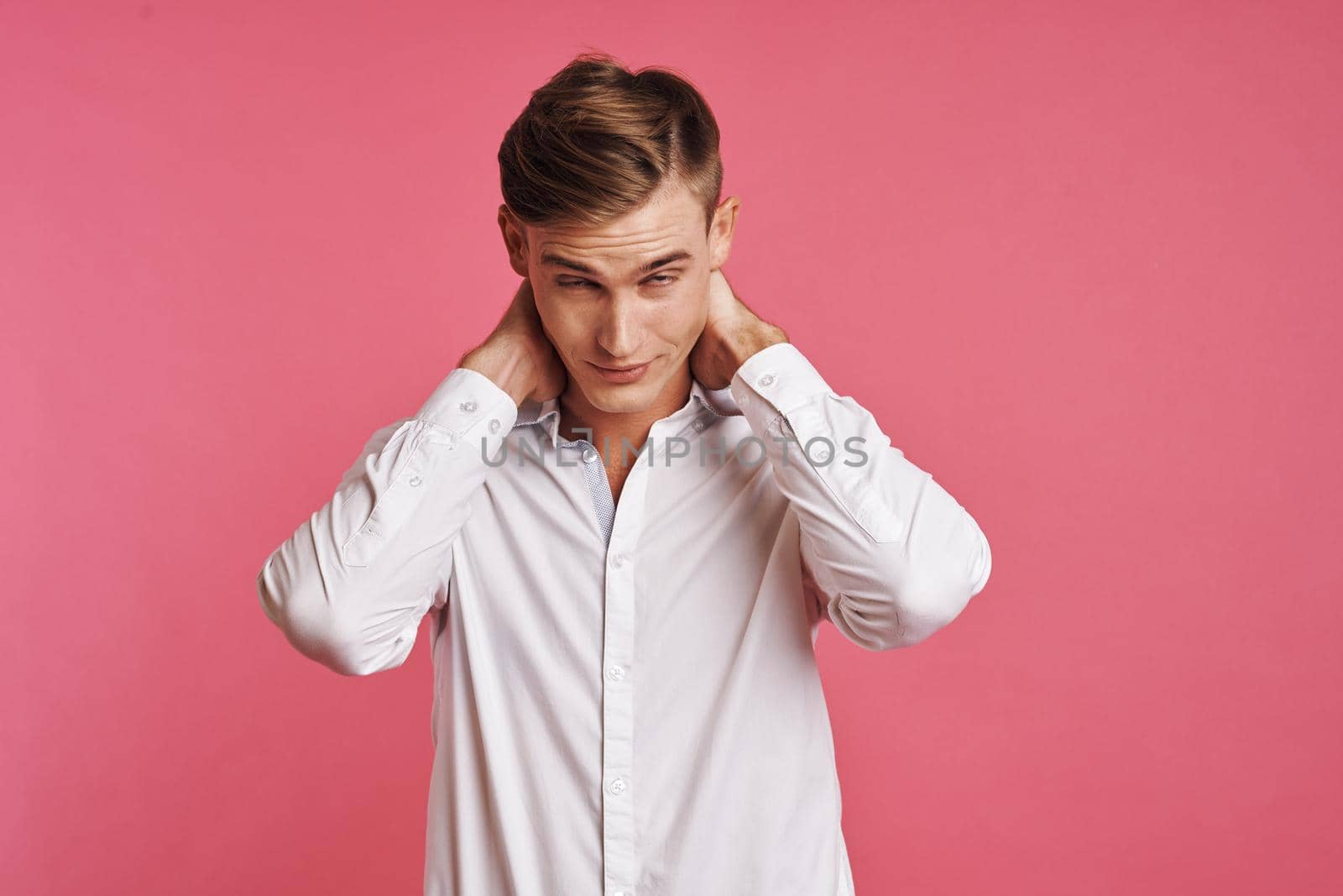 Young man in white shirt posing on pink background. High quality photo