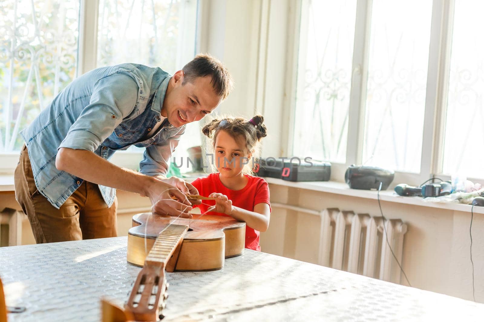 father and daughter repairing a guitar