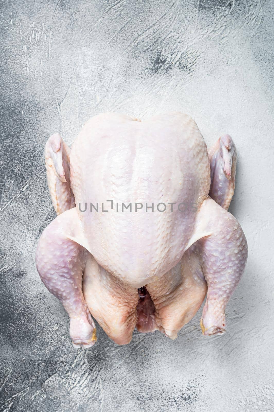 Raw free range whole chicken on a kitchen table. White background. Top view by Composter