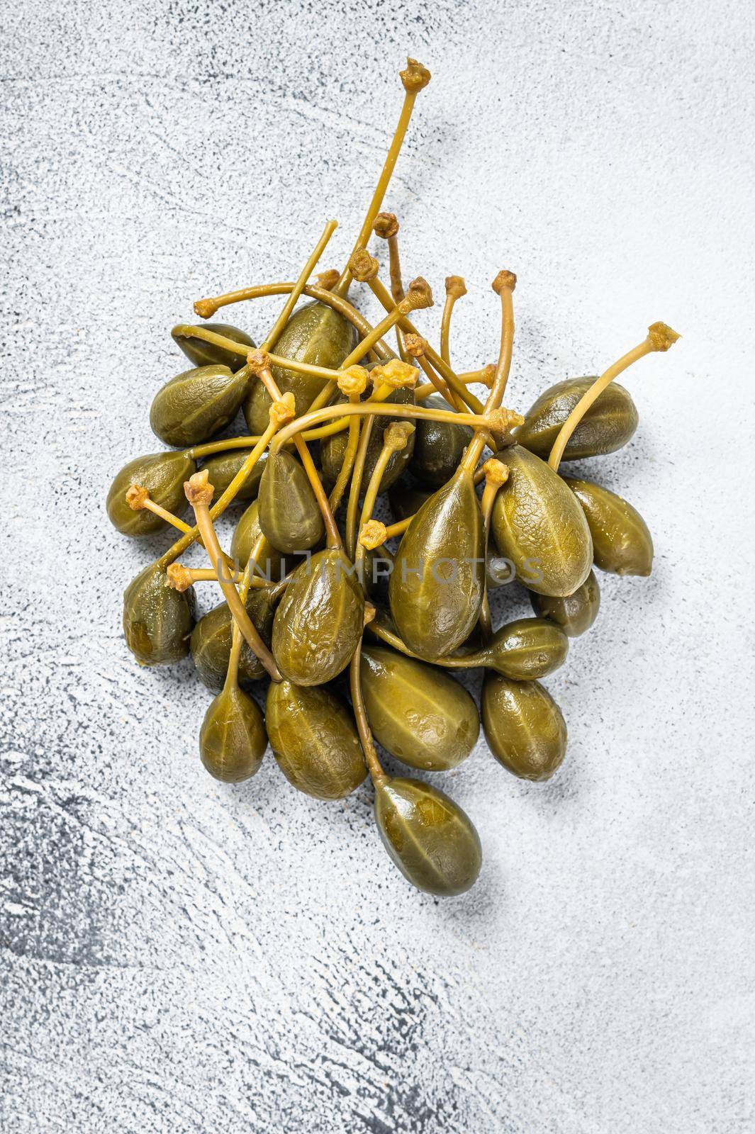 Pickled capers on a kitchen table. White background. Top view.