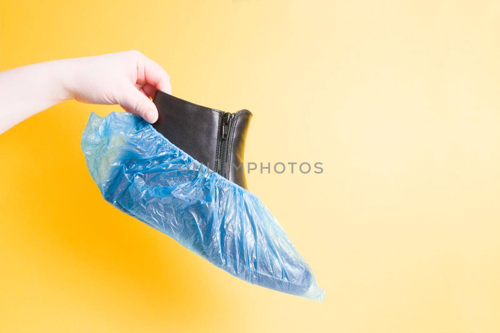 blue disposable shoe covers on a yellow background copy space by natashko