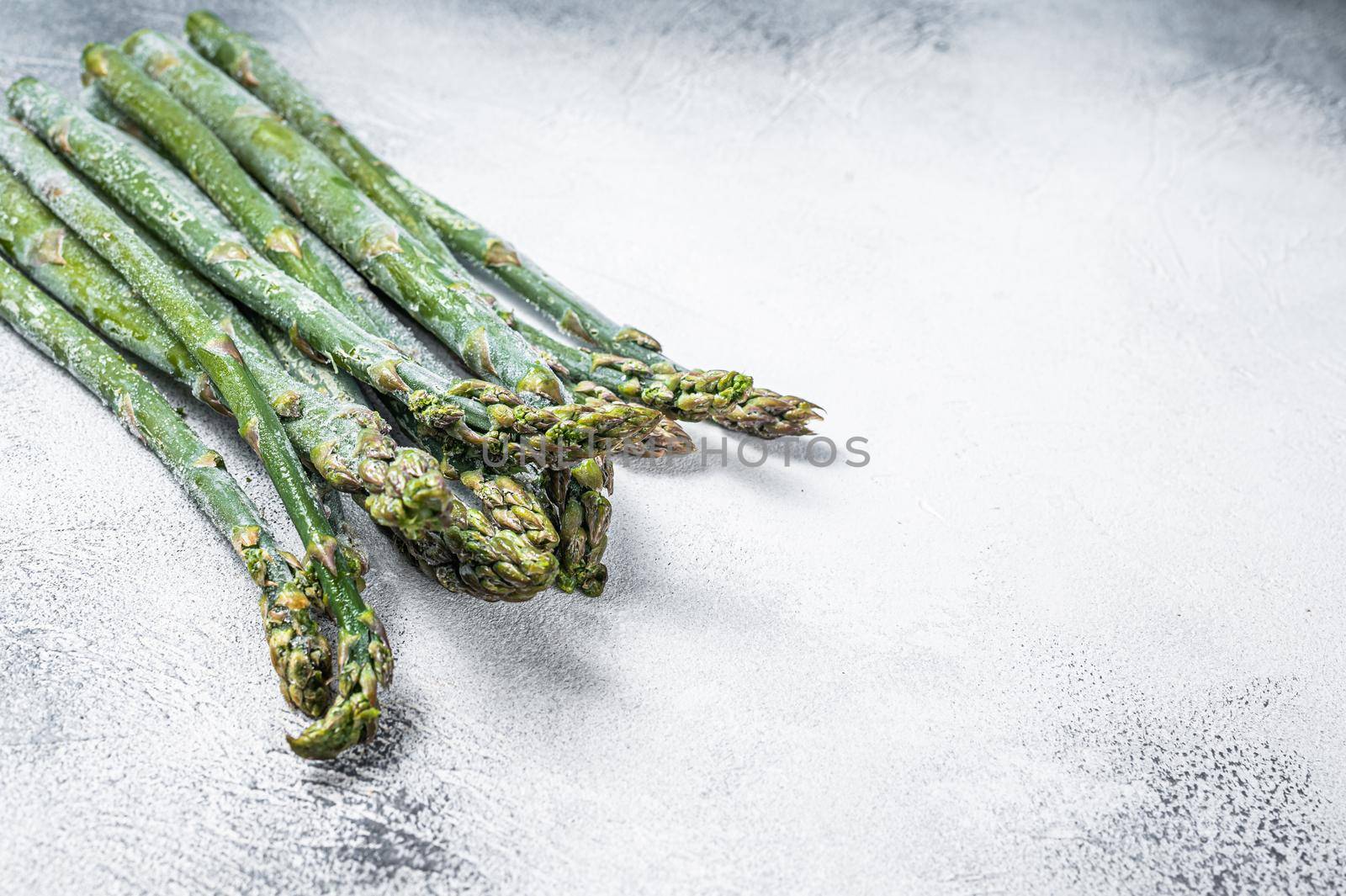 Frozen cold asparagus on a old kitchen table. White background. Top view. Copy space.