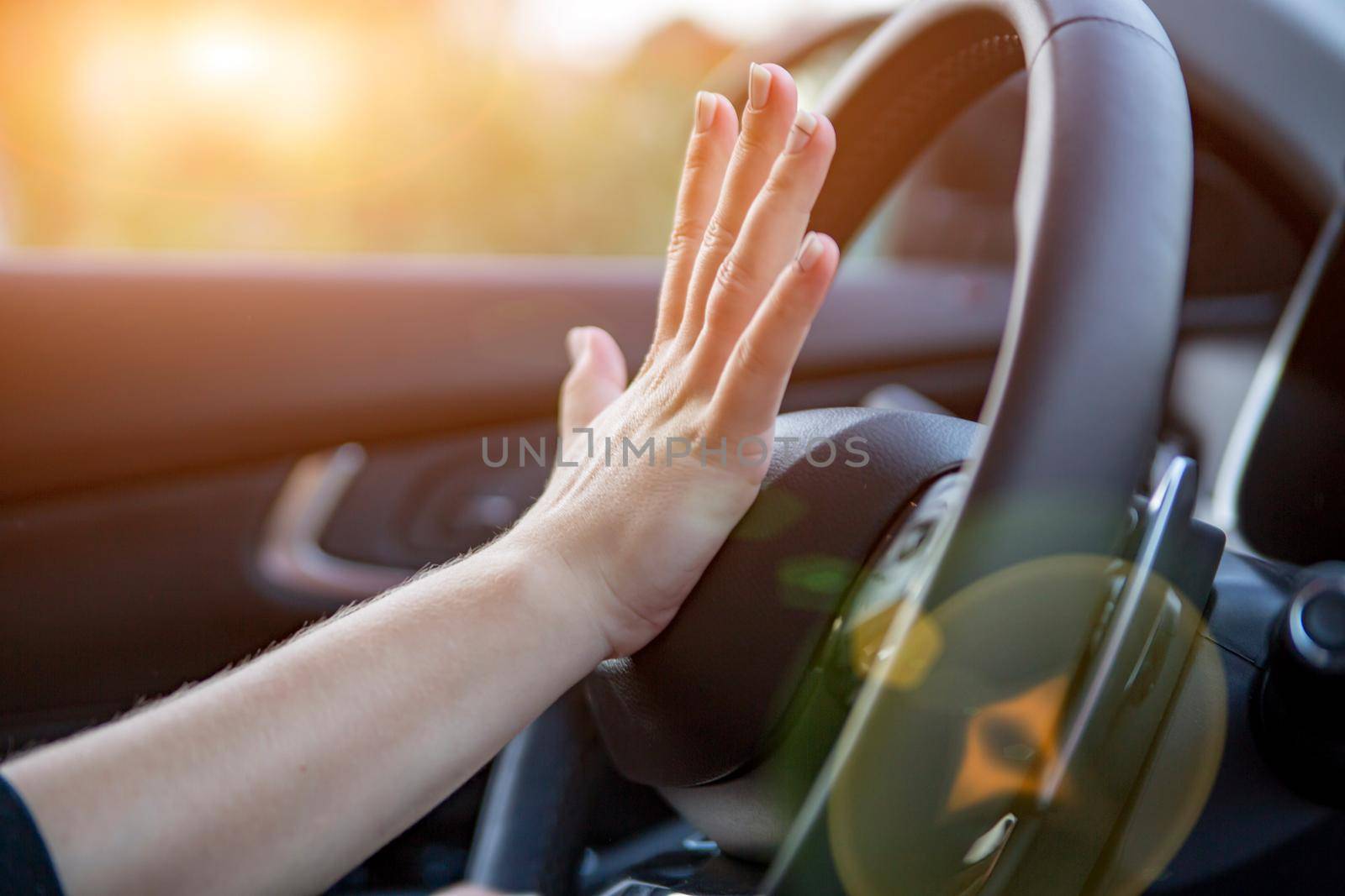 female hand presses the horn on the steering wheel of a modern car. no face