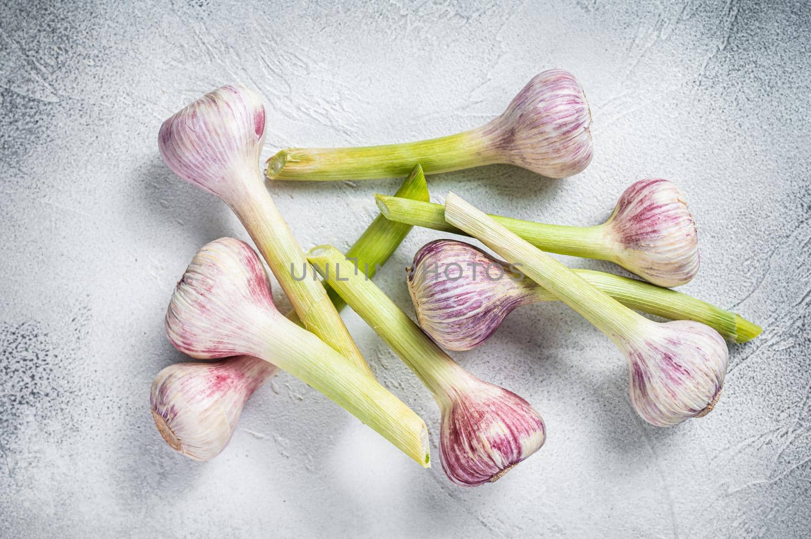 Fresh Spring young garlic bulbs on kitchen table. White background. Top view.