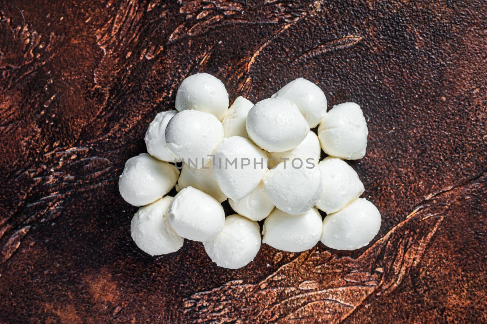 Buffalo mozzarella cheese mini balls on kitchen table. Dark background. Top view by Composter