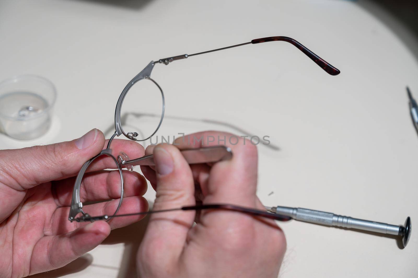 Installation of nose pads in glasses. A male technician repairs broken glasses.