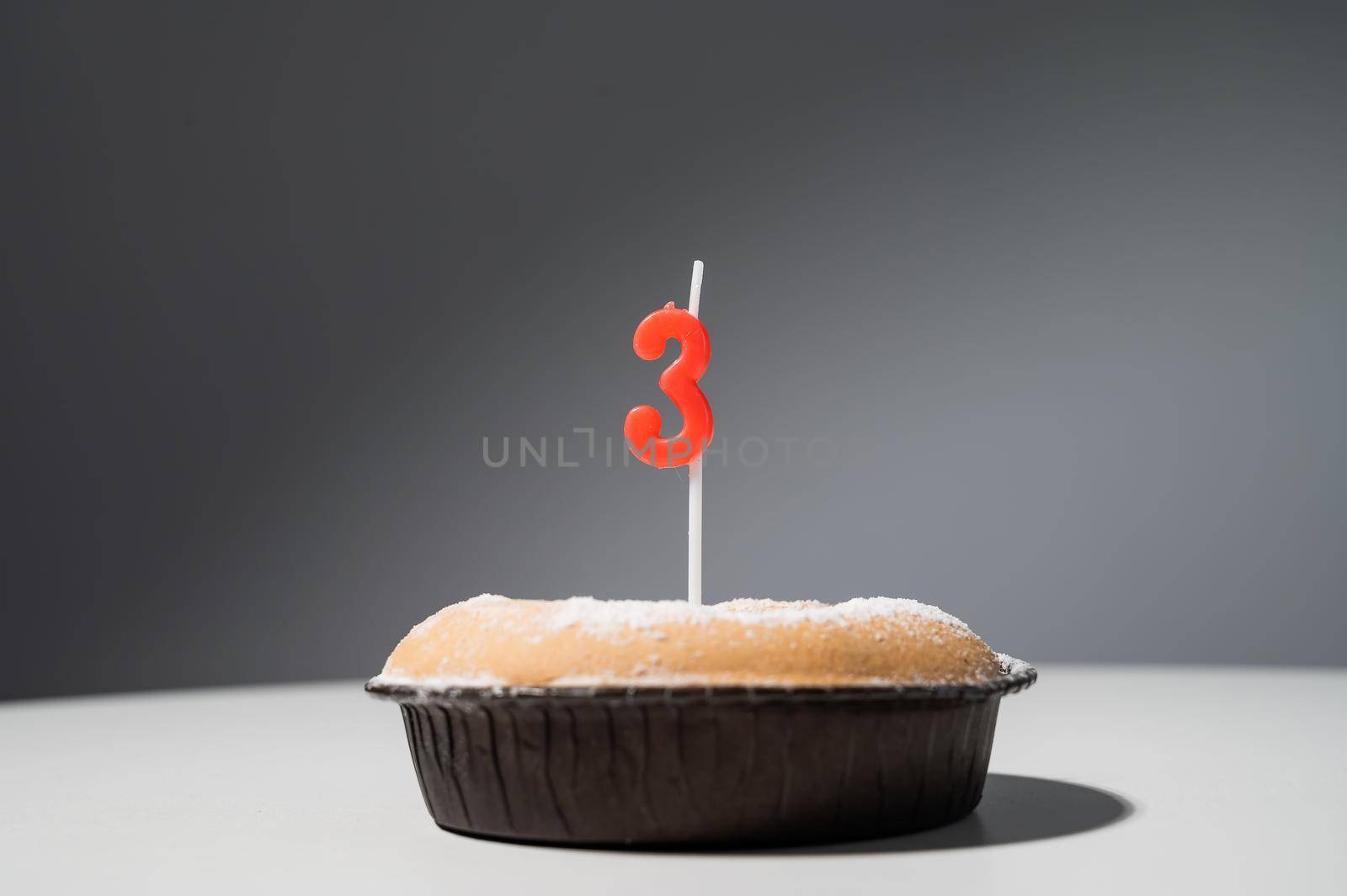 small cake with a candle in the shape of the number three for birthday