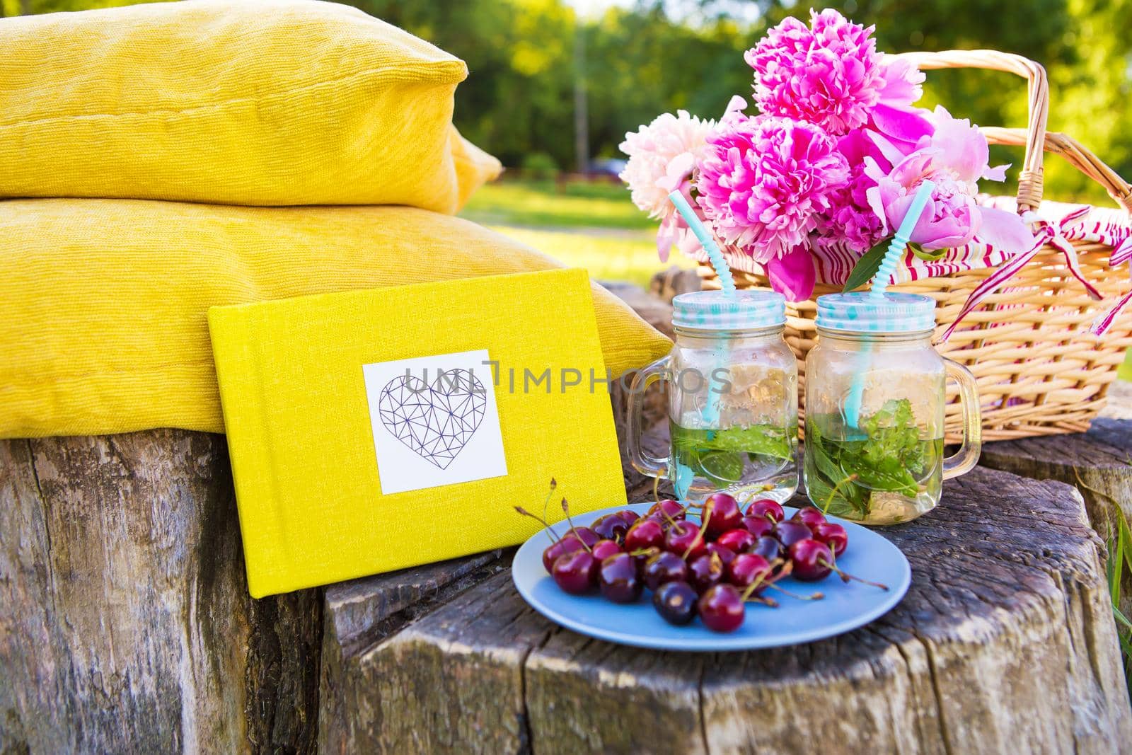 Picnic on the grass. Cherry, bouquet of flowers, fruit, book drinks