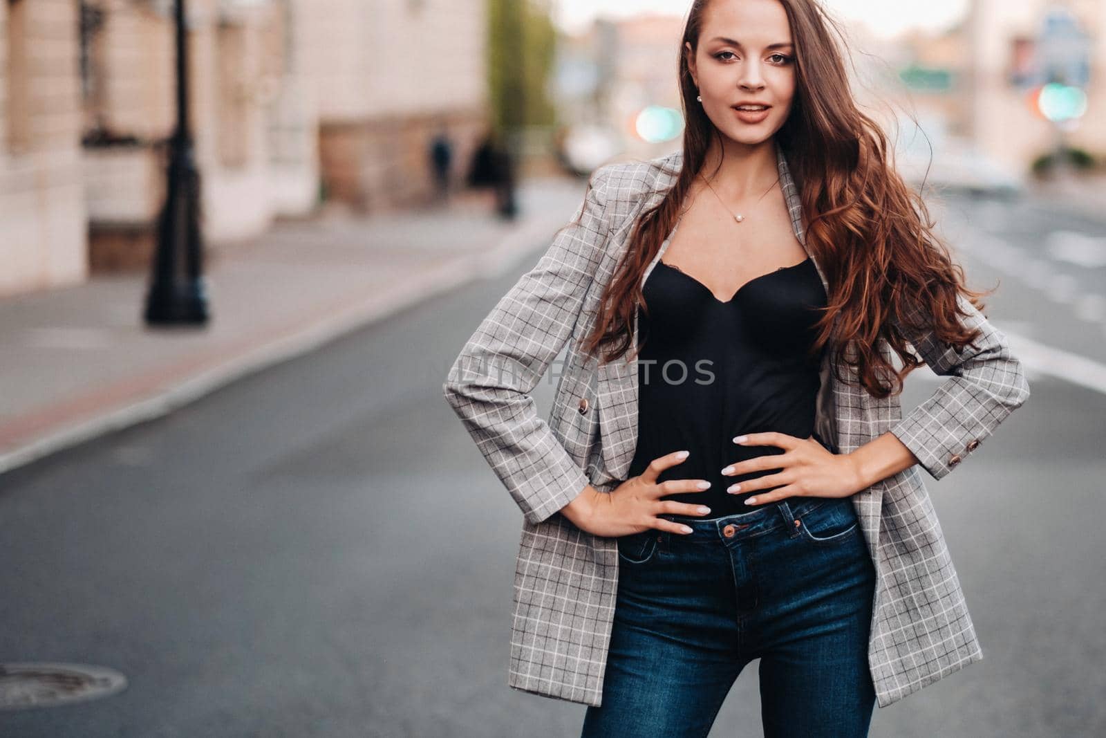a girl in a jacket and long hair walks through the old city.A beautiful girl smiles.Girl on the road.