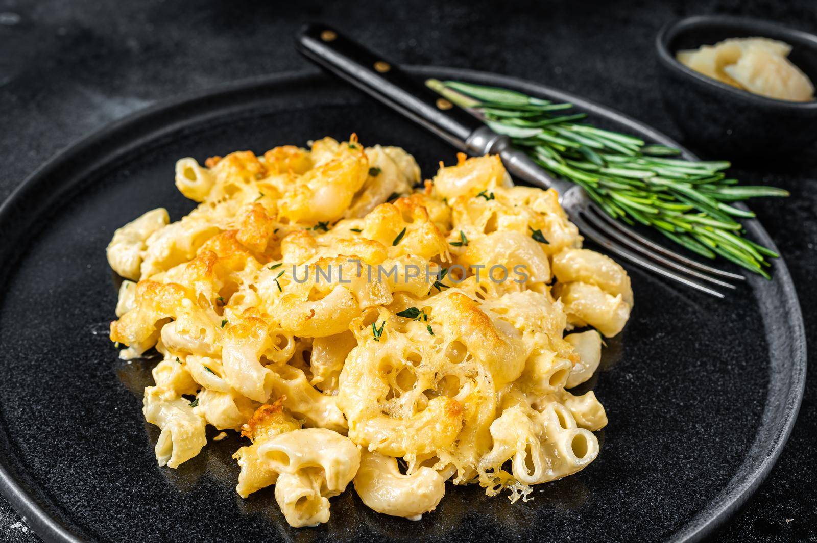 Baked Macaroni Mac and cheese American dish with Cheddar cheese sauce. Black background. Top view.
