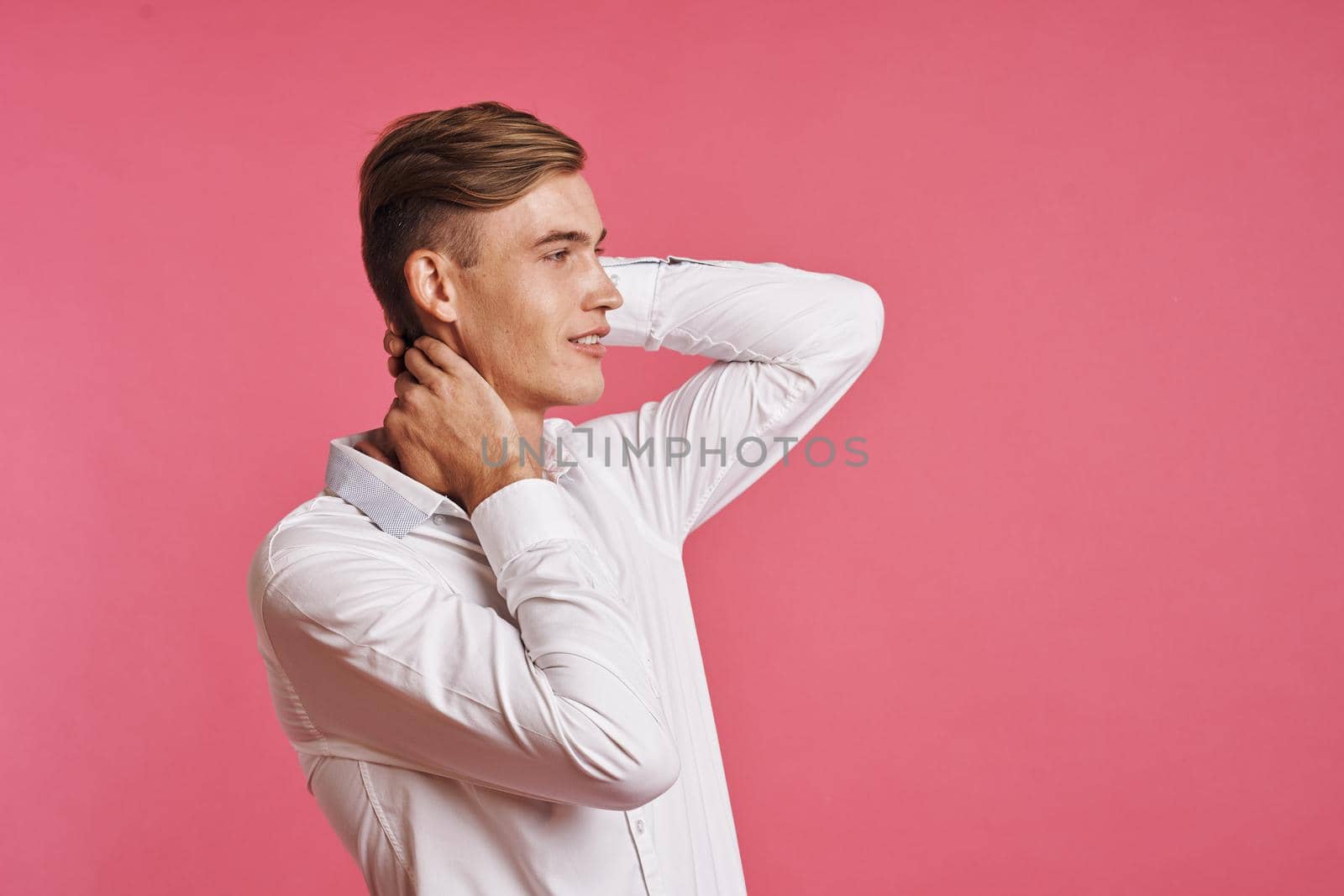 Young man in white shirt posing on pink background. High quality photo