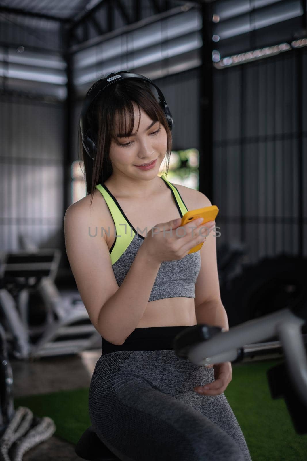 Beautiful sporty woman using phone checking her work between sport biking fitness at gym. by itchaznong