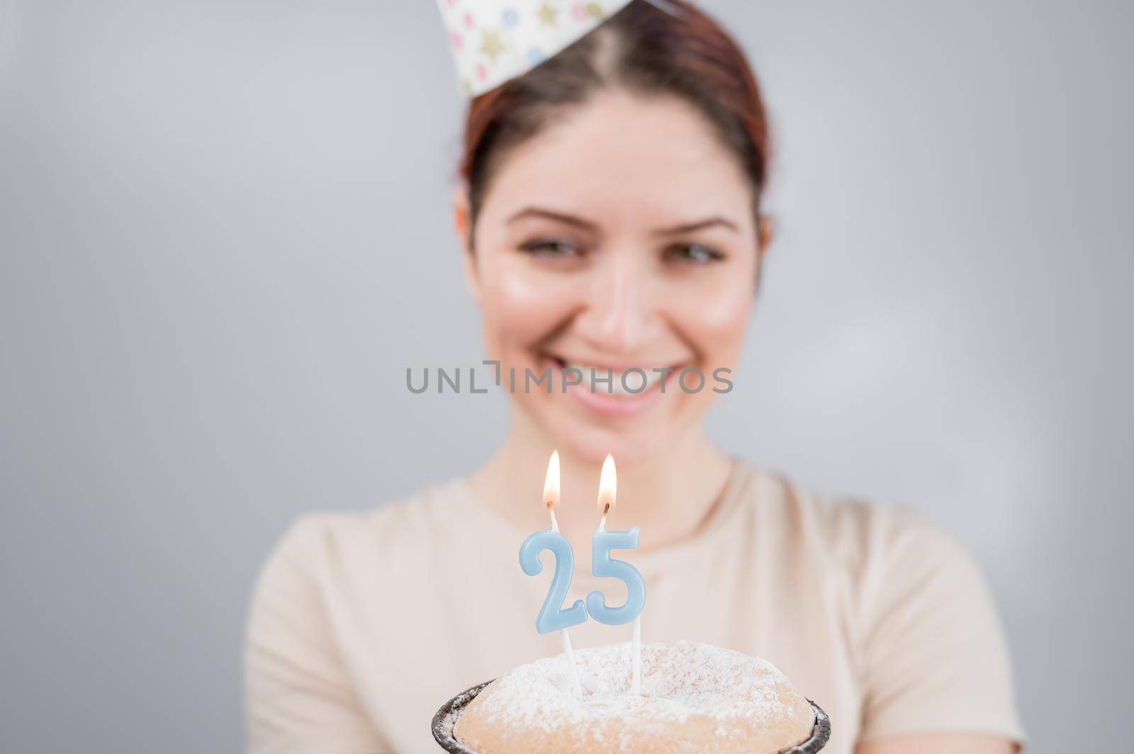 The happy woman makes a wish and blows out the candles on the 25th birthday cake. Girl celebrating birthday. by mrwed54