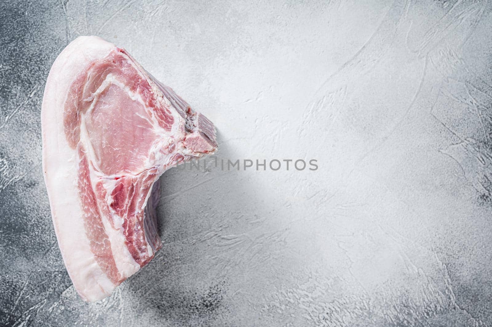 Raw whole rack of pork loin with ribs on kitchen table. White background. Top view. Copy space by Composter